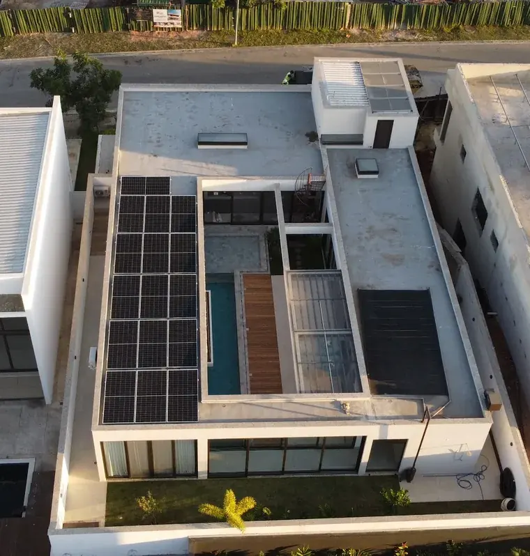 Vista aérea ao entardecer de residência moderna com piscina em Votorantim/SP, com 16 módulos fotovoltaicos na laje da cobertura