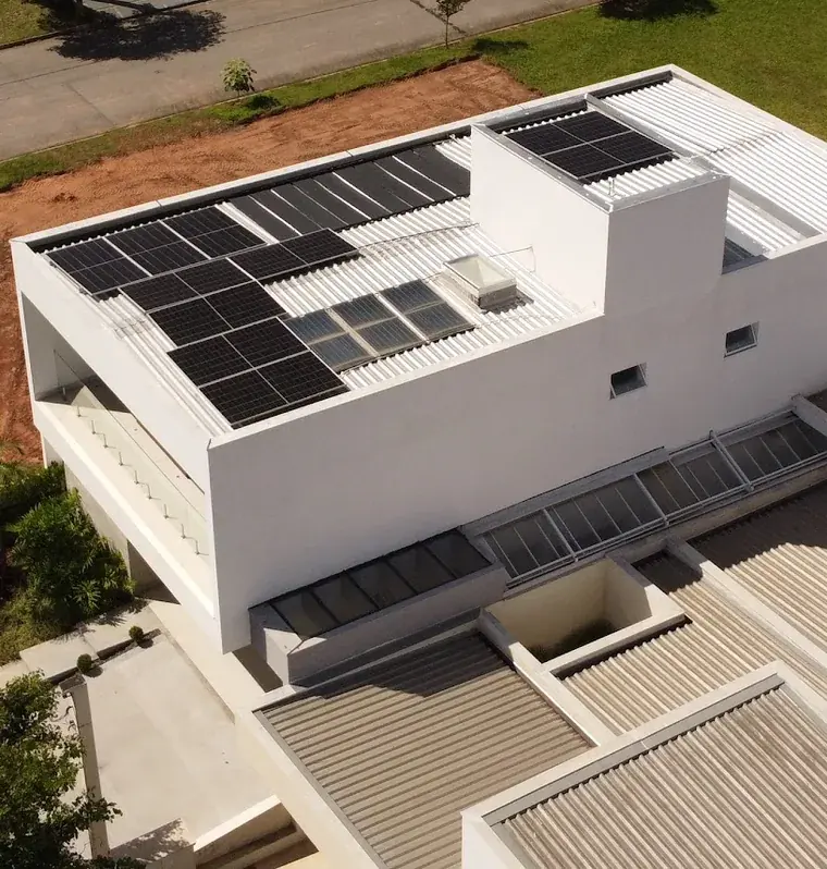 Vista aérea de residência branca de esquina em condomínio de Sorocaba/SP com módulos fotovoltaicos na cobertura