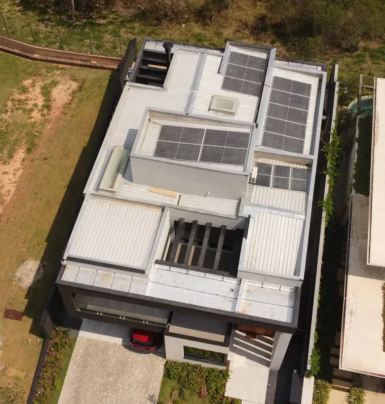 Vista aérea de residência moderna em Votorantim/SP com módulos fotovoltaicos em várias áreas do telhado metálico